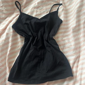 Svart linne - Säljer en stilren svart top med smala axelband. Ett måste i garderoben för alla som älskar enkel och elegant stil!