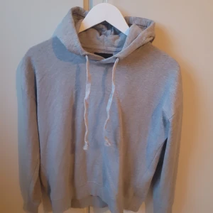 Grå hoodie från 157 - Säljer en grå hoodie från 157 i storlek M. Den är supermjuk och perfekt för kyliga dagar. Hoodien har en klassisk design med snören i huvan och ribbade muddar vid ärmslut och nederkant. Perfekt för både vardag och mysiga hemmakvällar!