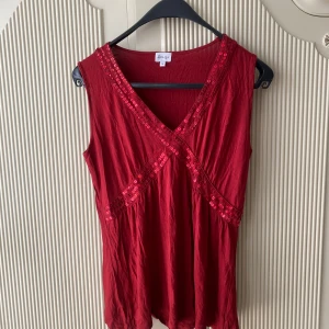 Röd paljettlinne - Snygg rött paljettlinne från Amalia med glittriga paljettdetaljer. Storlek M.