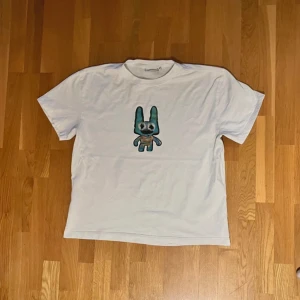 Weekday t-shirt  - Tisha vit från weekday med en liten söt figur på! Köpt i Stockholm och är helt Oanvänd, storlek M och passformen är boxy! 