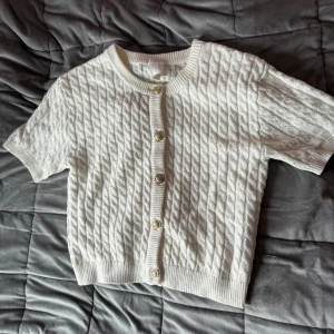 Ärmlös kofta - Den virala tröjan från H&M! Jättefin vit färg med guldiga detaljer, har inte kommit till användning så säljer nu vidare!