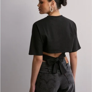 Open Back Tie Tee - Säljer denna efterfrågade toppen från Nelly i nyskick, endast använt 1 gång!