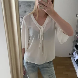 Vit blus med knytning - Säljer en superfin vit blus med trekvartsärm och snygg knytning framtill. Perfekt för både vardag och fest! Blusen har en lös passform och är gjord i ett lätt och bekvämt material. några få noppror på tröjan men inget man tänker på. 