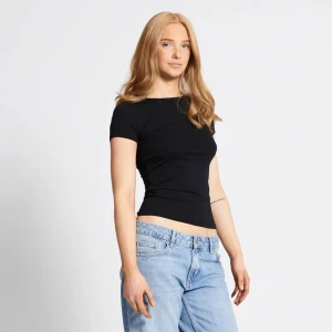 Svart topp med rosett - Säljer en snygg svart topp med korta ärmar och en stor rosett i ryggen. Toppen är tight och perfekt för en utekväll eller fest. Den har en öppen rygg som ger en extra touch av stil.