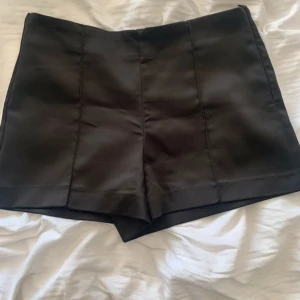 svarta glansiga kostymshorts - Svarta glansiga kostymshorts som är jättesnygga och coola. Storlek M men passar S beroende på hur man vill att dom ska sitta.