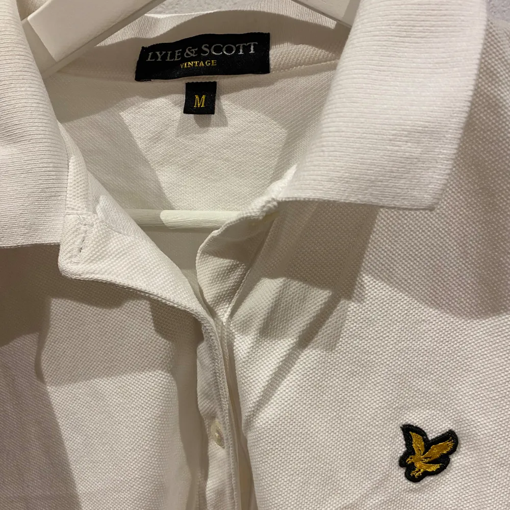 Säljer en klassisk vit pikétröja från Lyle & Scott i storlek M. Tröjan har en stilren design med den ikoniska loggan broderad på bröstet. Perfekt för både vardag och lite finare tillfällen. Skön och bekväm passform! Kan gå ner i pris vid snabb affär!. T-shirts.