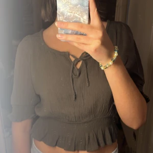 Supersöt top från Only - Säljer en superfin brun/grön topp från Only. Den har trekvartsärmar och en söt knytning framtill. (Bild 2 har skugga på sig och är lite otydlig)