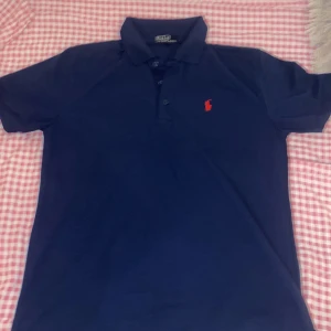 Ralph Lauren Piké  - En sprillans ny pike från Polo Ralph Lauren i färgen mörkblå med en röd logga, storleken är L men skulle säga att den kan passa XL skicket är 10/10 och aldrig använt, kontakta mig vid frågor⭐️🙌