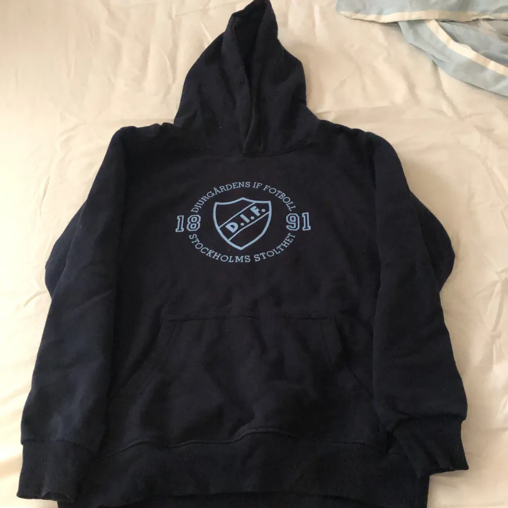 Säljer en svart hoodie med Djurgårdens IF Fotboll-logga på bröstet. Den har en stor ficka fram och en mysig huva. Perfekt för kalla dagar eller när du vill visa ditt stöd för laget!. Tröjor & Koftor.