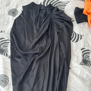 Svart kjol - Kjolen är lång, lite skrynklig framtill, har dragkedja bak, aldrig använd