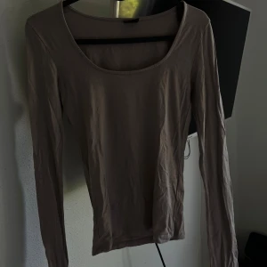 Långärmad topp från Gina Tricot - Säljer en stilren och bekväm långärmad topp från Gina Tricot. Den finns i två färger: en i en mjuk beige ton och en i klassiskt svart. Toppen är i storlek XS och har en normal passform.