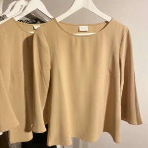 Beige topp från VILA - Säljer en stilren beige topp från VILA med trekvartsärm. Perfekt för en elegant och enkel look. Toppen har en rund halsringning och är i ett mjukt material.