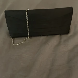 Svart handväska  - Köpte på secondhand. Väskan är lite sönder men det går att limma. Knappen är manganet så enkelt att stänga. Den har inget märke 