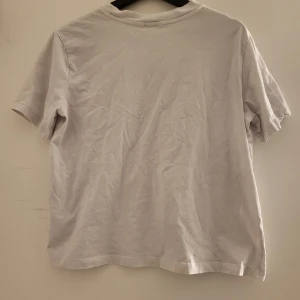 Vit t-shirt med tryck 'Venice Los Angeles, CA' - Säljer en vit t-shirt med texten 'Venice Los Angeles, CA' i grönt och svart. T-shirten har en klassisk rund hals och korta ärmar. Perfekt för en avslappnad stil.