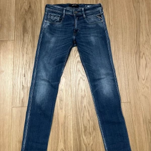 Blå jeans från Replay - Säljer ett par snygga blå jeans från Replay, modell Anbass. De har en klassisk femficksdesign med knappgylf och en bekväm passform. Perfekta för en stilren look. Mycket fint skick Storlek 30/32