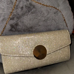 Glittrig kuvertväska - Glittrig kuvert väska från Tiamo. Oanvänd, har endast några repor på den guldiga detaljen, men annars i topp skick. 