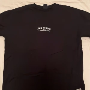 Svart t-shirt från Black Squad - Säljer en svart t-shirt från Black Squad med texten 'Drip Too Hard' tryckt i vitt på både fram- och baksidan. T-shirten har en normal passform. Perfekt för en avslappnad stil.