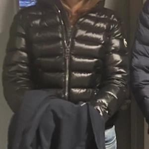Glansig colmar jacka  - Svart colmar jacka köpt förra vintern, älskar den men tyvärr är den för liten. Köpt för  4600. Bild 1-3 visar bäst hur den ser ut. Står tyvärr ingen storlek i jackan och kommer inte ihåg, men från armen upp till axeln/armhålan, är den ca 60cm, och längden är 57cm. Den har en liten defekt på ena ärmen men inget som syns eller känns över huvud taget. Säljer den för 2600. Skriv för frågor☺️