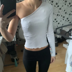Vit oneshoulder topp - Snygg vit oneshoulder topp i ribbat material. Perfekt för fest eller liknande tillfällen. Köpt för några år sedan men använts endast ett fåtal gånger. Inget tecken på användning.