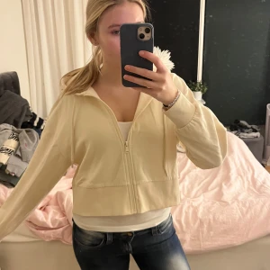 Beige hoodie med dragkedja - Säljer en beige hoodie med dragkedja framtill. Den har en avslappnad passform och långa ärmar. Perfekt för en casual look. Skriv om ni har några frågor!💞