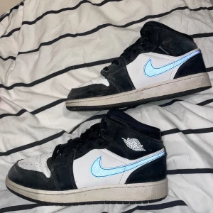 Nike Air Jordans med blå Swoosh - Snygga Nike Air Jordans i svart och vitt med en iögonfallande blå Swoosh. Skorna har snörning och en klassisk design som passar perfekt för sneakerälskare. Äkta oxå!!!