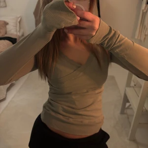 Grön omlottopp - Säljer en stilren grön omlottopp med långa ärmar. Toppen har en v-ringad design. Den är både bekväm och trendig.