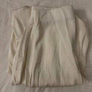 Vit kjol från Stockholm Studio - Elegant vit kjol från Stockholm Studio i storlek XS. Kjolen har en stilren design med dragkedja baktill för enkel på- och avtagning. Perfekt för en minimalistisk look.