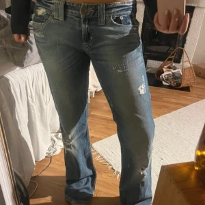 Lågmidjade jeans - Säljer ett par blå bootcut jeans med slitningar och låg midja. Perfekta för en avslappnad stil. Köpta på vinted men passade ej. Är i storlek 38 eller en stor 36. Obs läs vad som står på min profil💗Pris går att diskutera💗