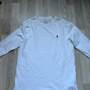 Vit långärmad tröja från Polo Ralph Lauren - Säljer en klassisk vit långärmad tröja från Polo Ralph Lauren. För liten för mig nu men Perfekt för en stilren och avslappnad look.