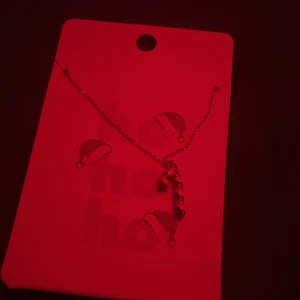 Halsband med polkagrisberlock - Charmigt halsband från Accessoires med en polkagrisberlock. Perfekt för julens festligheter. Kedjan är tunn och elegant, vilket gör den lätt att bära.