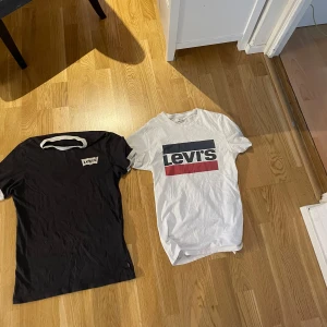 Två Levi's t-shirts i svart och vit - Säljer två snygga Levi's t-shirts. En svart med klassisk logga i vitt och en vit med logga i blått och rött. Perfekta för en casual look. Båda är kortärmade och i bomull. 35kr st paketpris 60kr