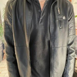 Svart skinnjacka helt oanvänd  - Snygg svart skinnjacka med dragkedja och en stilren design. Jackan har en mjuk, pälsliknande insida för extra värme och komfort. Perfekt för kyligare dagar.