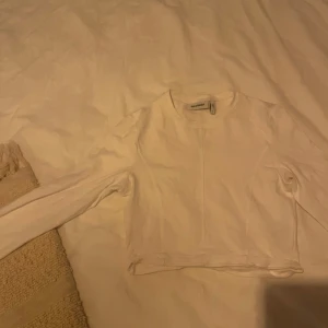 Vit croppad tröja från Weekday - Säljer en stilren vit croppad tröja från Weekday. Tröjan har långa ärmar och en enkel design som passar perfekt till vardags. Perfekt för lager-på-lager-stil eller att bära som den är.