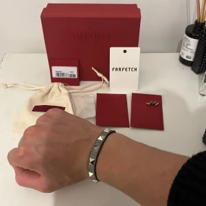 Valentino armband  - Säljer detta sjukt feta Valentino armbandet i grå färg, skick 7,5/10, allt og ink extra nitar, från farfetch. Kan gå ner vid snabb affär!