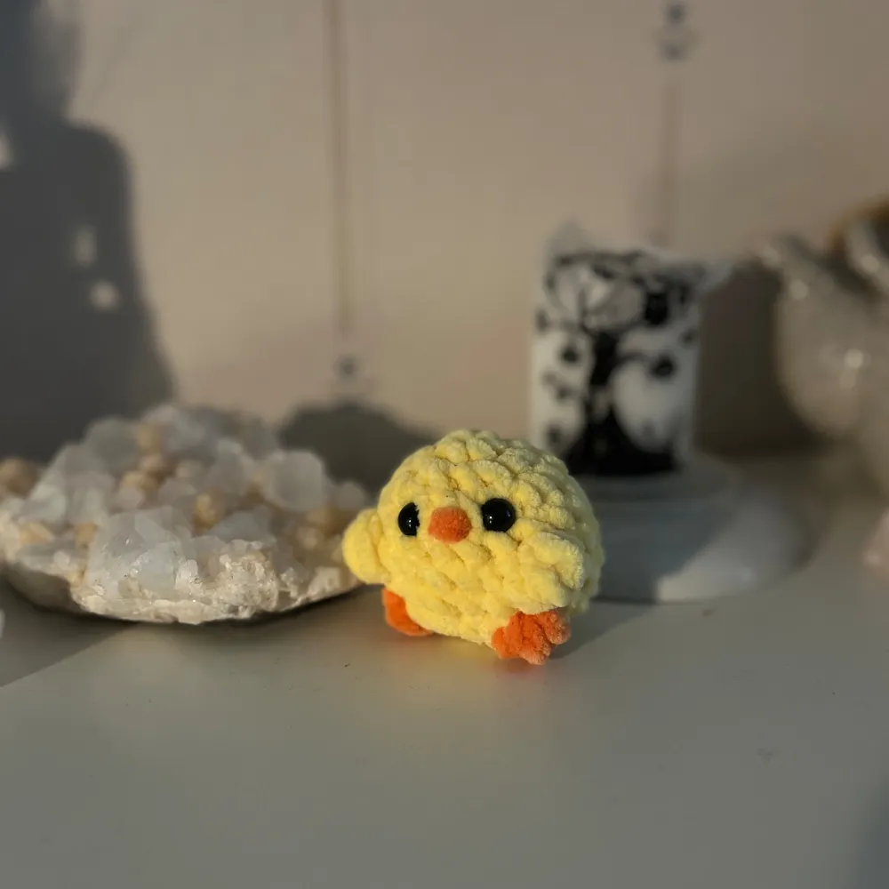 En supergullig liten gul virkad kyckling med svarta ögon och orange näbb och fötter. Perfekt som dekoration eller present! 🐥. Accessoarer.