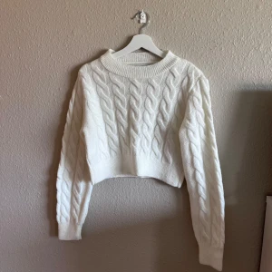 Vit stickad tröja - Säljer en superfin vit stickad tröja med flätmönster. Den är croppad och har långa ärmar, perfekt för höst och vinter. Tröjan är både mysig och stilren, passar till alla tillfällen!