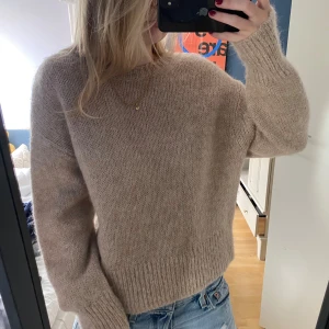 Beige stickad tröja från H&M - Säljer en supermysig beige stickad tröja från H&M. Den är perfekt för höst och vinter med sin varma och mjuka alpaca-ullblandning. Tröjan har långa ärmar och ribbade muddar som ger en skön passform. 🧡