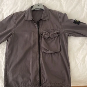 Stone Island overshirt  - Trodde jag aldrig skulle sälja denna pärla men efter två år har den blivit för liten för mig. Den här jättefina overshirt i en unik grå-lila färg är i super bra skick. Storlek M, nypris 3000kr.
