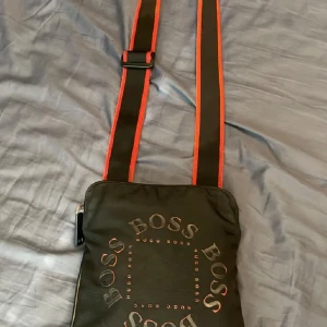 Hugo Boss väska svart röd. Sällsynt!! - Säljer min Hugo Boss väska som är väldigt svår att få tag på. Den har inga defekter samt fri från tobaksvaror. Varenda detalj sitter som den ska. Pris kan diskuteras vid seriöst köp!! Södertälje📍📍