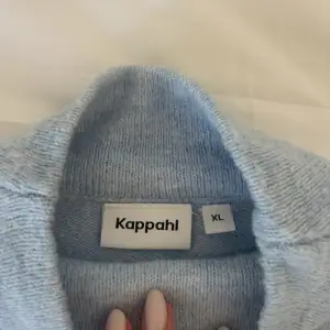 Säljer en supermysig ljusblå stickad tröja från Kappahl. Den har en hög krage och långa ärmar med ribbade muddar vid ärmslut och nederkant. Perfekt för kyliga dagar! 💙