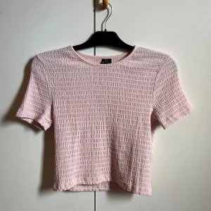 Ljusrosa ribbad topp från Vero Moda - Säljer en söt ljusrosa topp från Vero Moda. Den har en ribbad struktur och korta ärmar, perfekt för en avslappnad stil. Toppen är croppad. Skriv för fler bilder eller funderingar💕