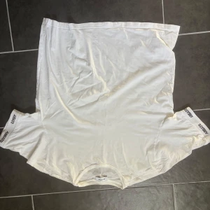 Vit t-shirt från Axel Arigato - Säljer en stilren vit t-shirt från Axel Arigato. T-shirten har korta ärmar med märkesnamnet tryckt längs ärmsluten. 