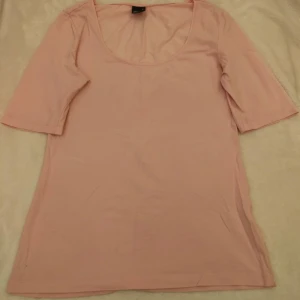 Rosa topp från Gina Tricot - Säljer en söt rosa topp från Gina Tricot. Toppen har en rund halsringning och trekvartsärmar, perfekt för en avslappnad stil. Materialet är mjukt och bekvämt. Storlek M.