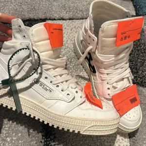 Vita sneakers från Off-White - Snygga vita sneakers från Off-White med hög design och tydliga orange detaljer. Skorna är köpt på mytheresa och är som nya. Har kvitto o box 