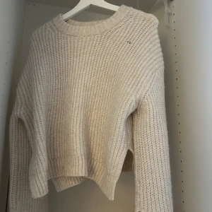 Beige stickad tröja - Mysig beige stickad tröja med ribbade detaljer. Perfekt för kyliga dagar med sin varma och bekväma design. Tröjan har en klassisk rund hals och långa ärmar. Vill tillägga som de kanske syns på bilden så har de ett litet hål vid nyckelbenet, därmed säljer jag den ganska billigt. 💞