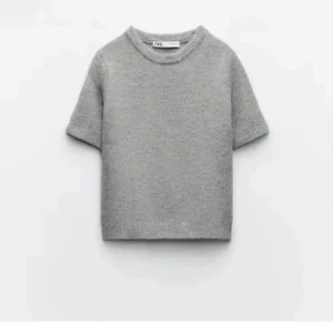 Grå stickad tröja från Zara - Säljer en stilren grå stickad tröja från Zara. Tröjan har korta ärmar och en rund halsringning, perfekt för lager-på-lager eller som den är. Enkel och tidlös design som passar till många olika stilar.