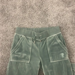 Gröna mjukisbyxor från Juicy Couture - Snygga gröna mjukisbyxor från Juicy Couture i mjukt material. Använd fåtal gånger. Säljer för dem är för små och inte kommer till användning. Dem är k storlek xxs. Frakten ingår i priset 