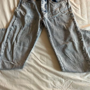 Ljusblå jeansbyxor - Säljer ett par ljusblå jeansbyxor med en klassisk femficksdesign. Byxorna har en straight passform och är tillverkade i denim. Perfekta för en avslappnad stil. Storlek 32L 32L
