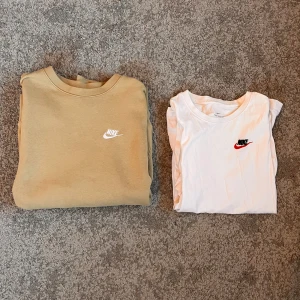 Beige sweatshirt och vit t-shirt från Nike - Säljer en beige sweatshirt och en vit t-shirt från Nike. Sweatshirten har långa ärmar och en rund halsringning med Nike-logga i vitt. T-shirten är kortärmad med en rund hals och har en Nike-logga i svart och rött. Sweatshirt för 175 och t shirt för 75, eller 200 för båda! Storlek xs men snarare S.