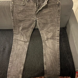 Gråa  jeansbyxor - Snygga svarta jeansbyxor med en klassisk design. De har en dragkedja och knappar framtill samt fem fickor. Perfekta för en avslappnad stil.